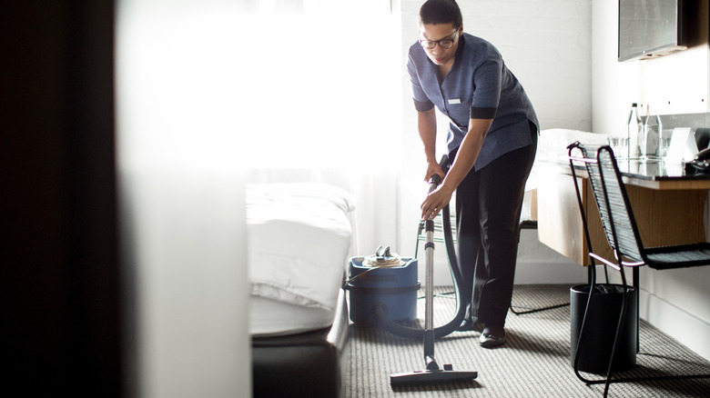 Hushållerska dammsuger hotellgolvet