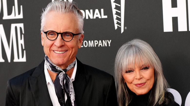 Pat Benatar och Neil Giraldo poserar för ett foto framför en svartvit bakgrund.