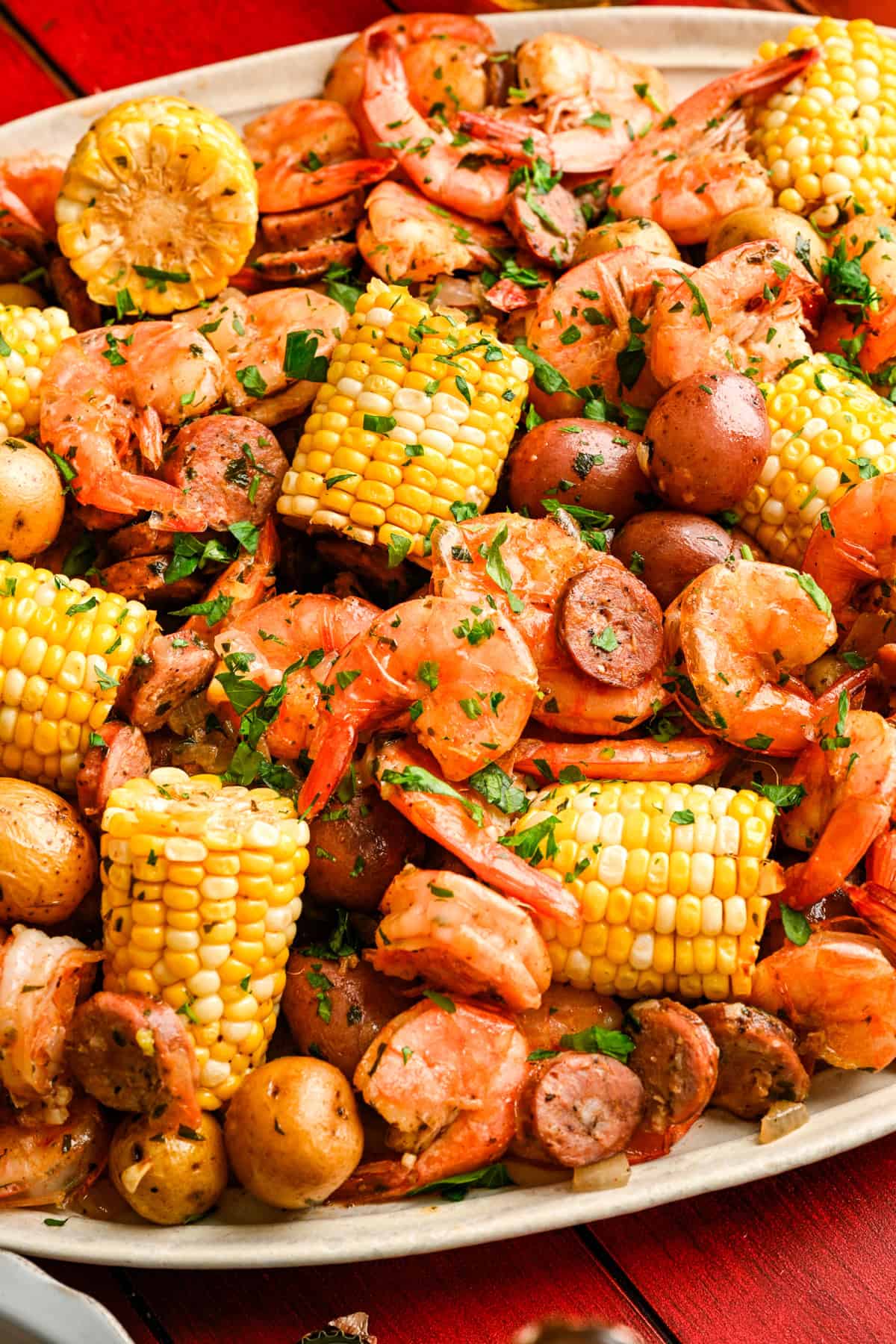 Närbild av arket pan räkor koka på ett fat med majs, räkor, korv och potatis.