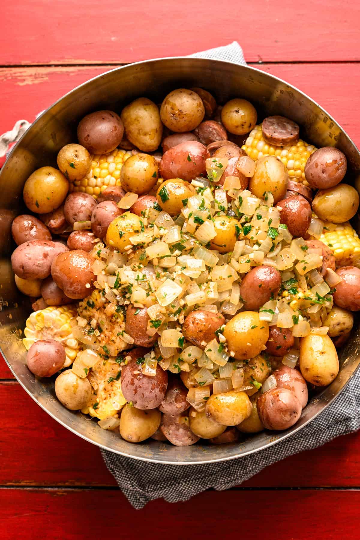 Räkor, majs, potatis och korv i en stor skål med gammal vitlökssmörsås hälld över toppen innan du blandar.