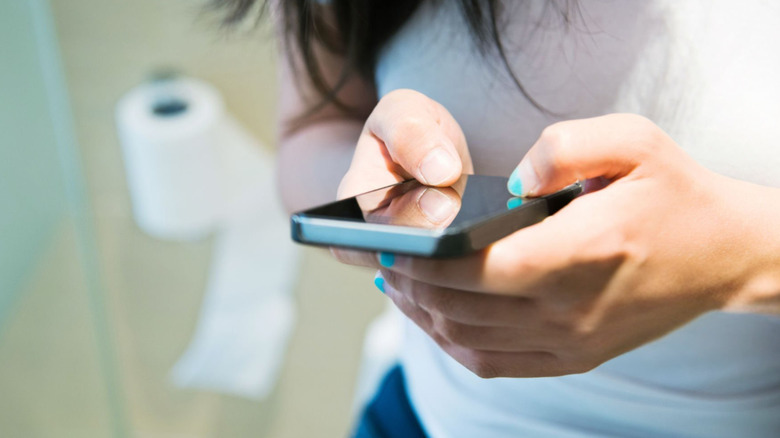 kvinnor som använder sin mobiltelefon på toaletten