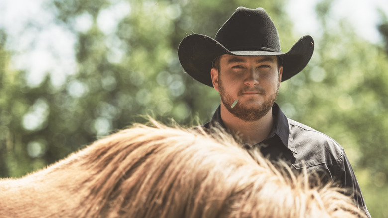 En cowboy som står bakom sin häst