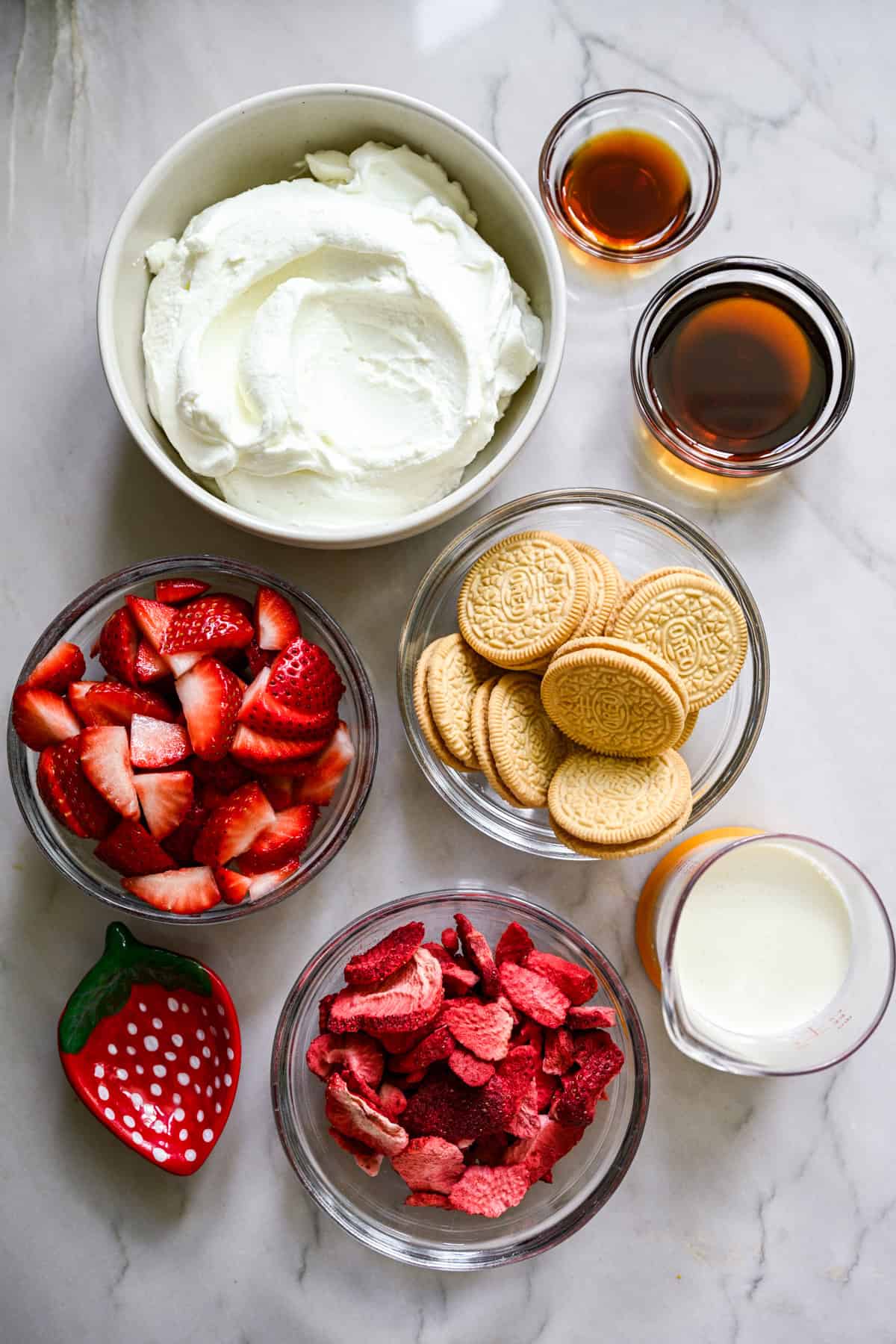 ovanifrån av ingredienser för strawberry shortcake glass barer i små förberedelser skålar.