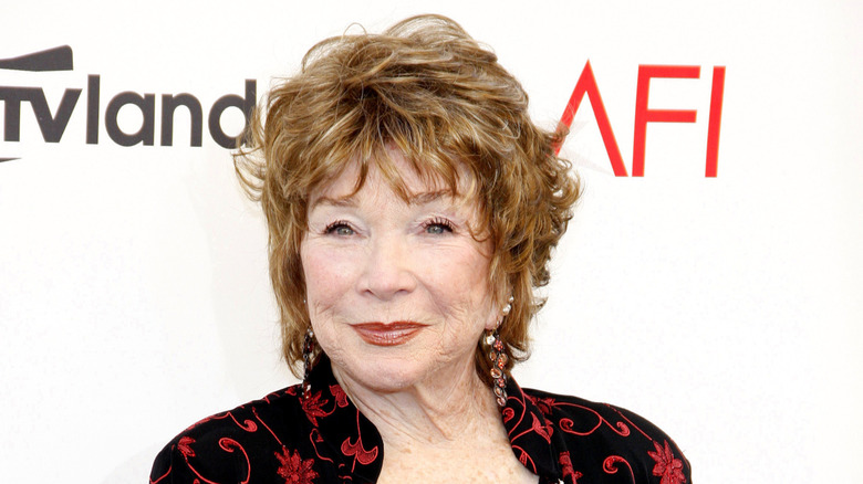 Shirley MacLaine poserar i en svart klänning med röda mönster vid den 40:e AFI-ceremonin.