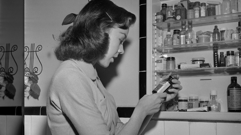 kvinna på 1950-talet tittar på produkter i medicinskåp