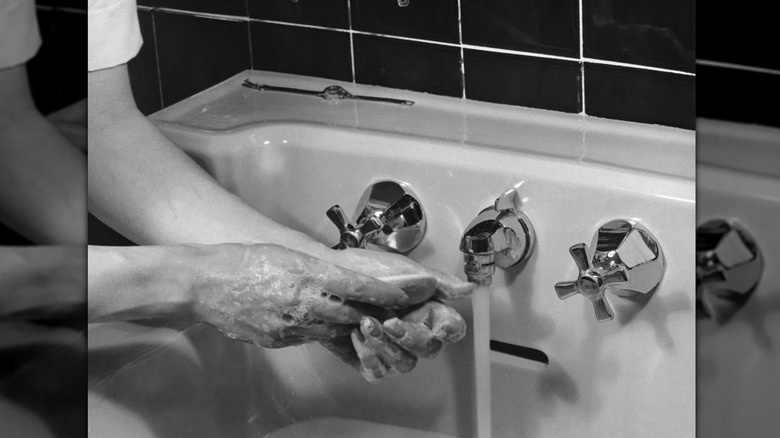 kvinna som tvättar händerna i 1950-talets handfat med tvål