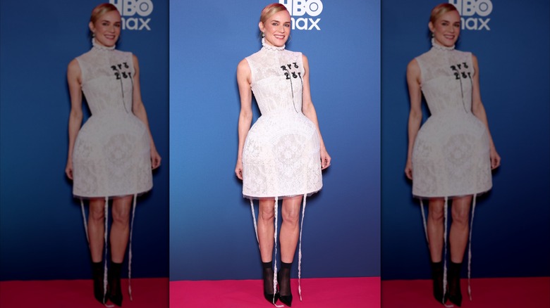 Diane Kruger på röda mattan iklädd en kort, vit spetsklänning med svarta stövlar.