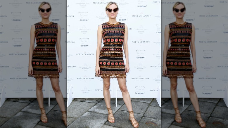 Diane Kruger på ett event iklädd en miniklänning med intrikat randmönster med solglasögon.