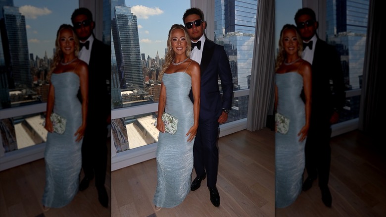 Brittany Mahomes och Patrick Mahomes poserar tillsammans framför ett fönster med utsikt över New Yorks skyline.