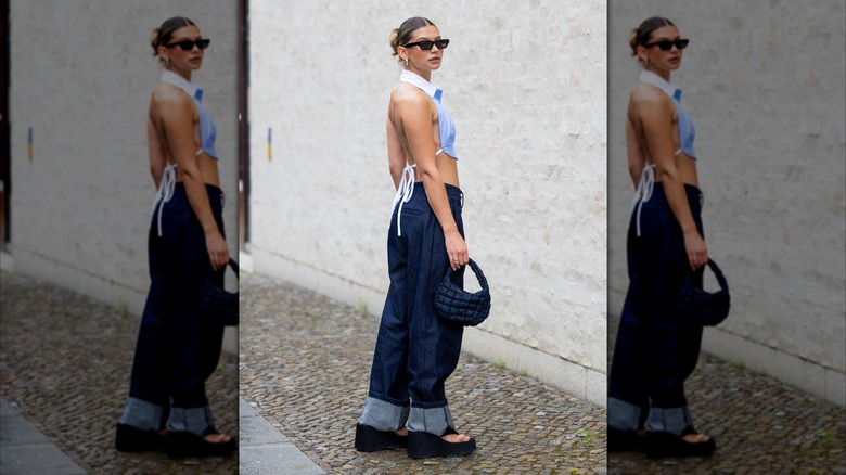 En kvinna på Berlin Fashion Week 2025 bär en ljusblå crop top med exponerad rygg och säckiga jeans.