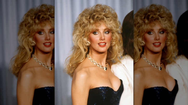 Morgan Fairchild poserar i en glittrande blå klänning med ett halsband i guldkedja.