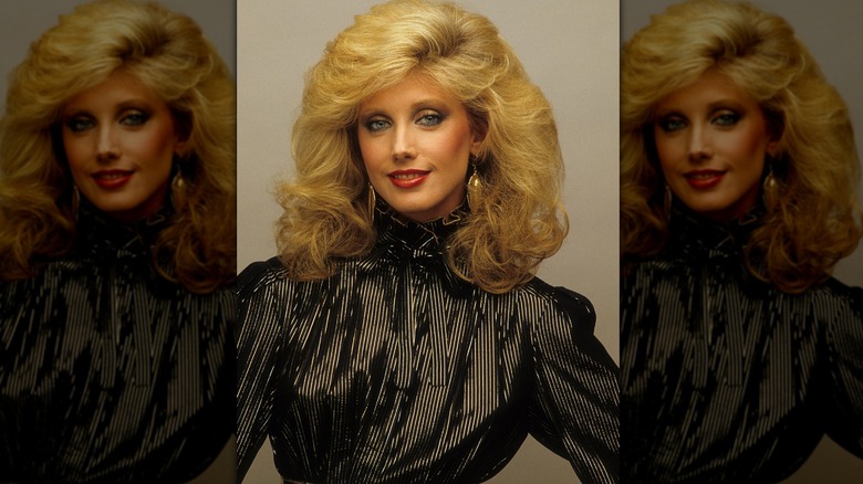 Morgan Fairchild poserar i en svart topp med guldörhängen.