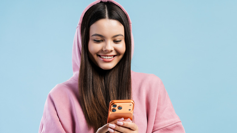 En tjej som bär en hoodie och håller en smartphone