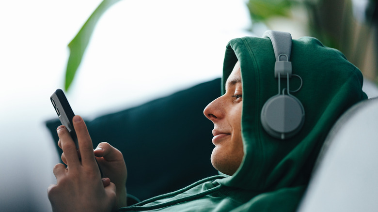 En ung man som bär hörlurar och skriver på sin smartphone