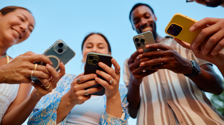 Fyra unga vuxna som använder smartphones