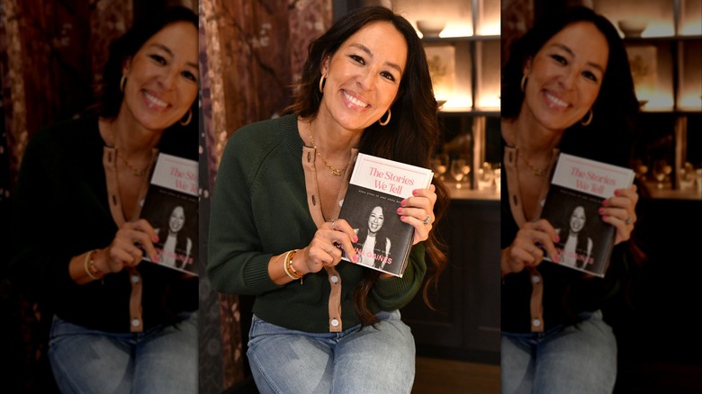 Joanna Gaines poserar med sin bok iklädd jeans och en mörkgrön tröja.