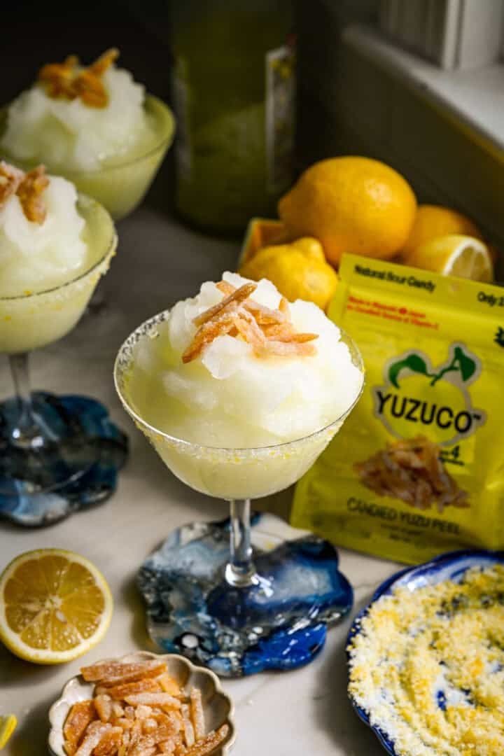 närbild av fryst limoncello cocktail i ett coupe glas med kanderad yuzu skal garnering.