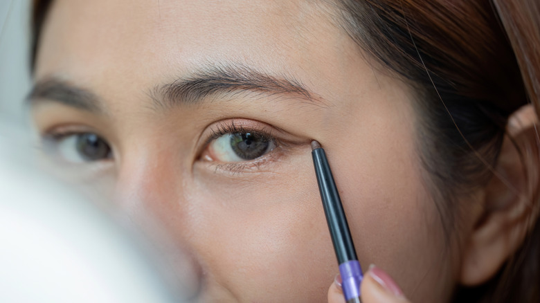 Närbild av kvinna som applicerar subtil eyeliner