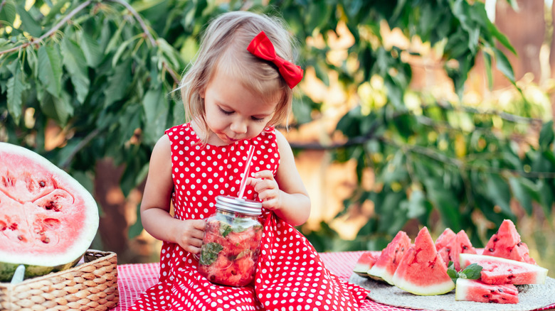 Söt barn äter mogen saftig vattenmelon på sommaren. Barn, baby, hälsosam mat mellanmål för barn. Bedårande liten flicka som försöker sälja lemonad