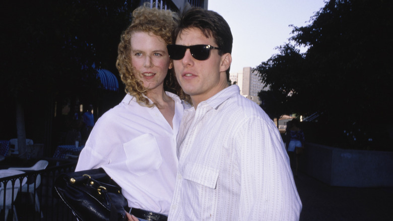 Nicole Kimdan poserar med Tom Cruise 1990, båda klädda i vita skjortor med knappar.