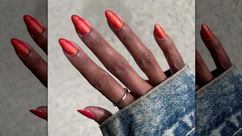 En hand som bär bränt-orange skimmer nagellack.