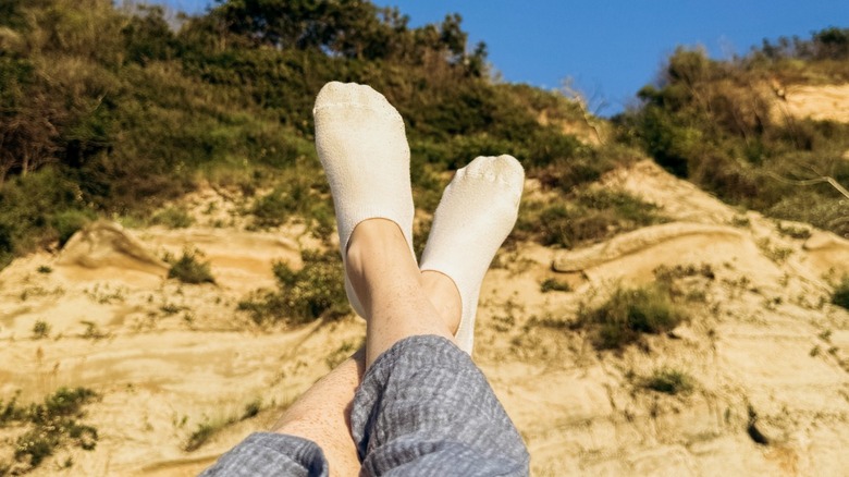 En person som bär vita strumpor medan han vilar på en sandstrand