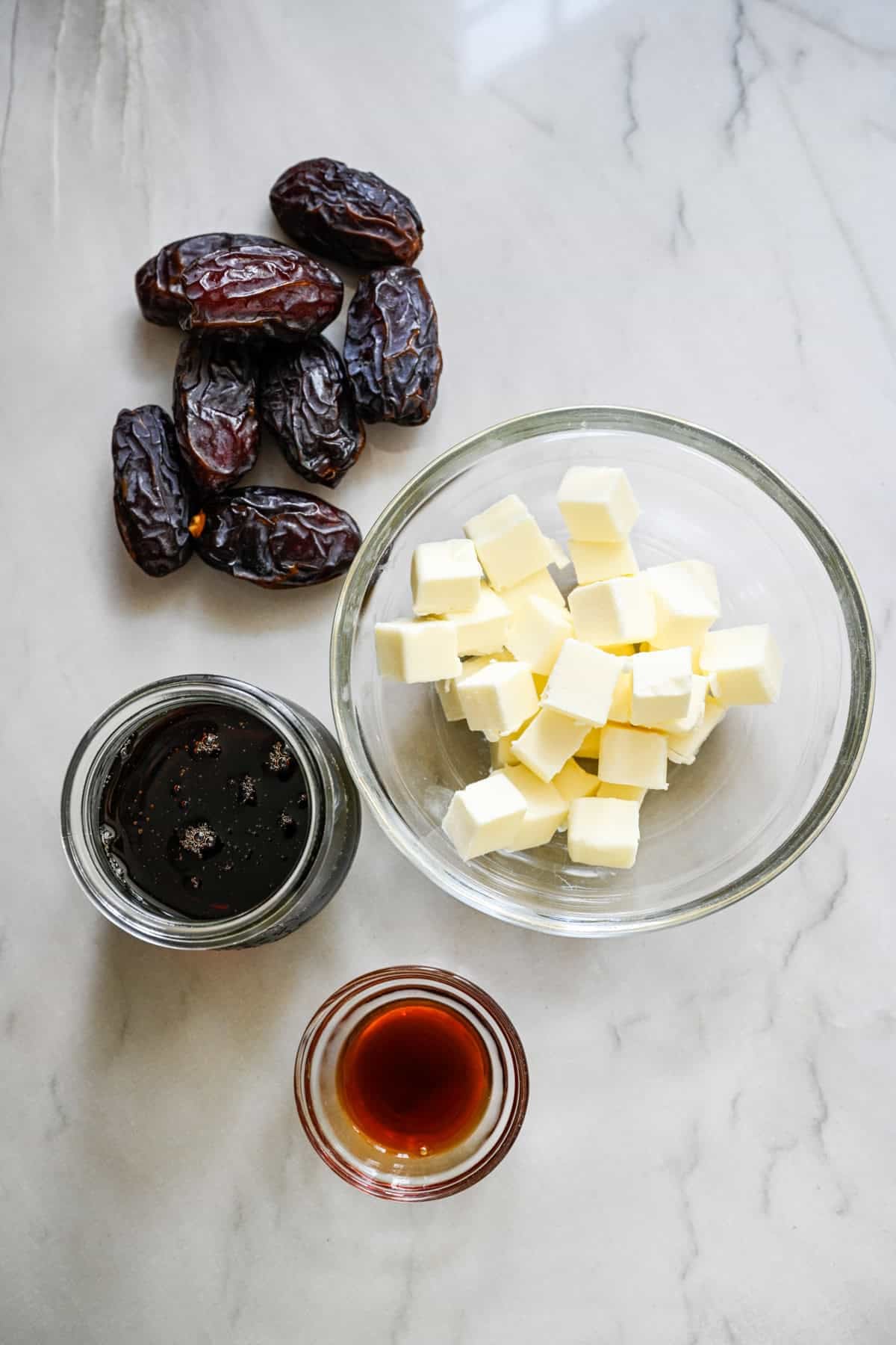 ovanifrån av smör, dadlar, lönnsirap och vaniljextrakt för att visa ingredienser till dadelkolasås.
