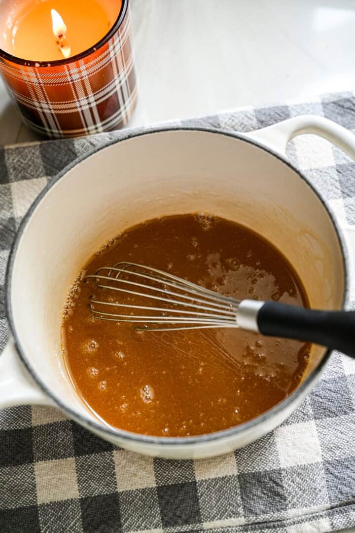 Smör och lönnsirap vispas ihop i en liten vit kastrull.