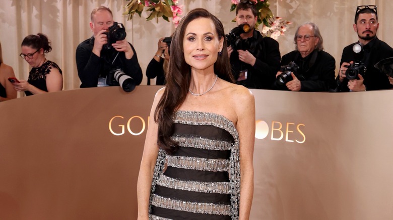 Minnie Driver poserar på röda mattan i en svart-silverrandig klänning.