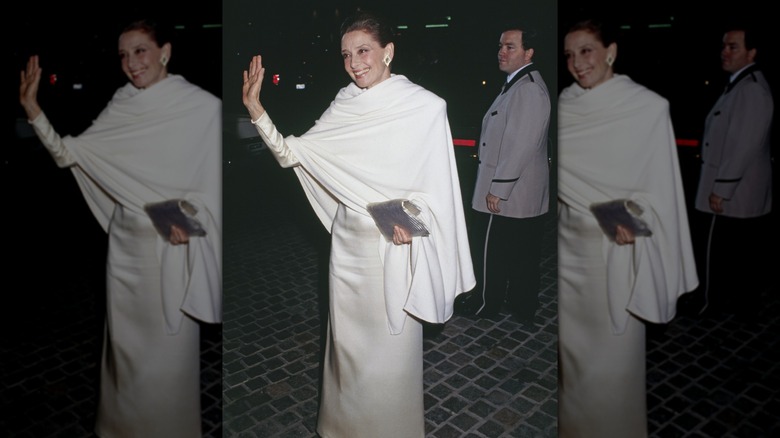 Audrey Hepburn på Golden Globes klädd i en vit klänning med en vit sjal, vinkar mot kamerorna.