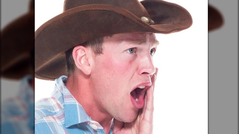 cowboy håller kinden i obehag och skriker