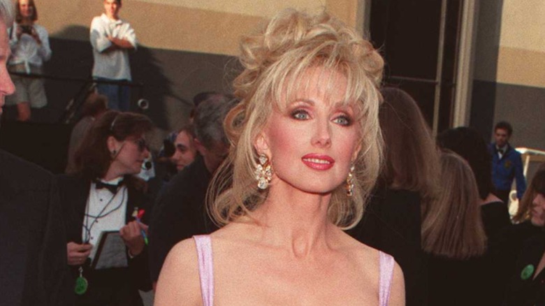 Morgan Fairchild 1996 på röda mattan med en stökig updo och pigg lugg.