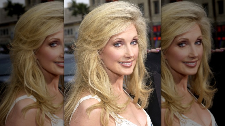 Morgan Fairchild 2023 med lätt fjäderhår klädd i en vit klänning.