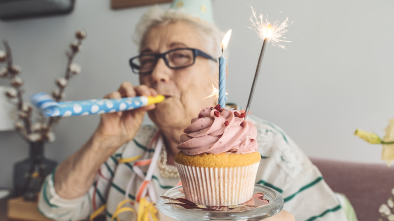 äldre kvinna firar ett speciellt tillfälle hemma med en cupcake