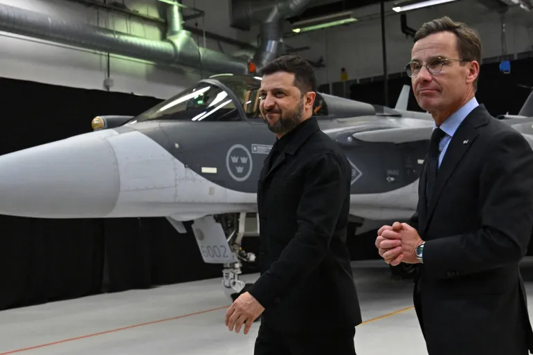 Sveriges statsminister Ulf Kristersson, till höger, och Ukrainas president Volodymyr Zelenskyy går förbi ett Gripen-stridsflygplan efter att de hållit en gemensam presskonferens i Linköping, Sverige