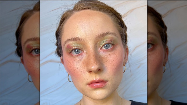En person med fräknar och strålande ögonmakeup som poserar för en bild