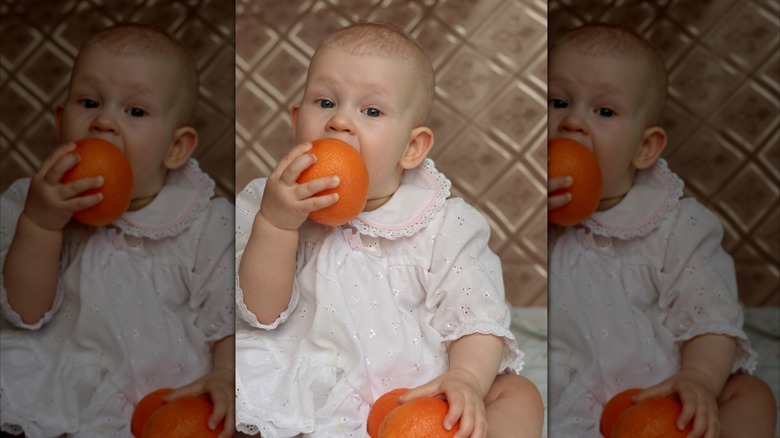 Baby äter en apelsin