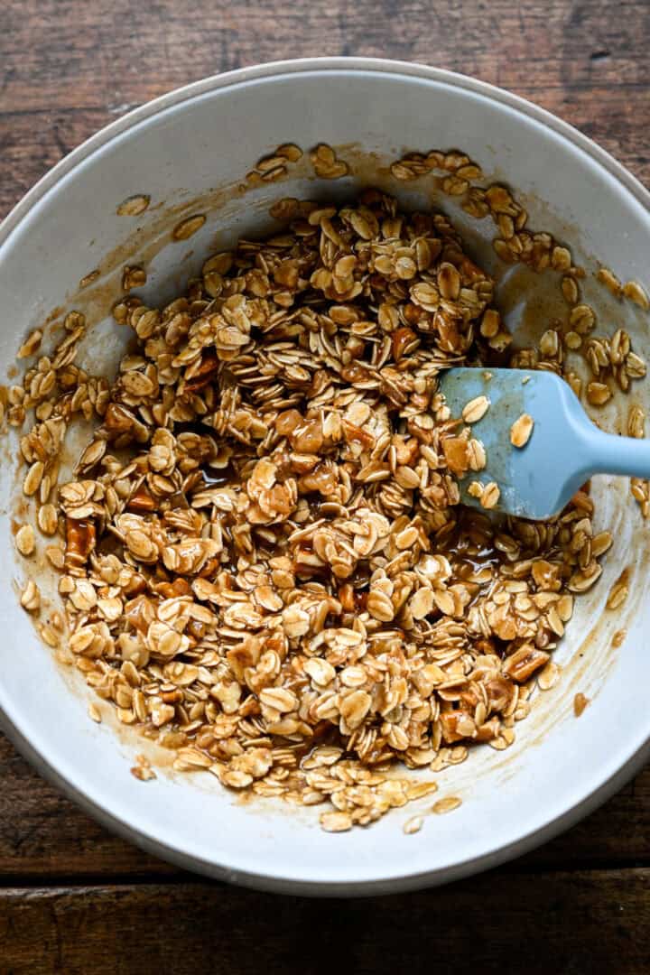 Havreblandningen rörs ut med smör och sirap tills den är klibbig och klumpat ihop sig.