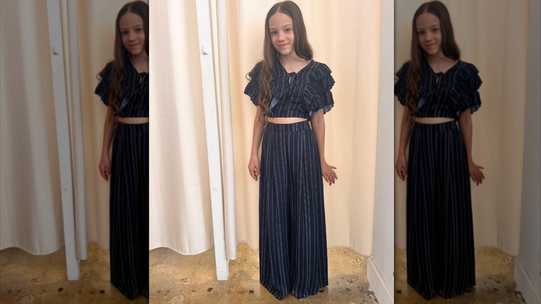 Skywalker Hughes ler i en tvådelad marinblå outfit med kritränder.