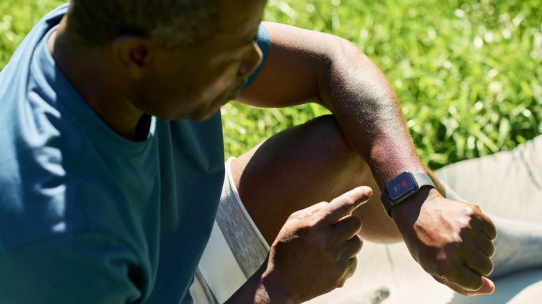 ung man kontrollerar hälsoappen på sin smartwatch