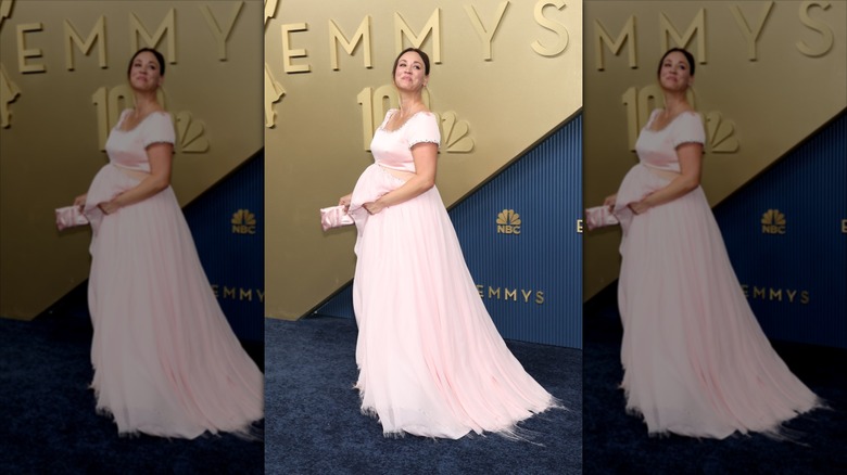 Kaley Cuoco ler iklädd en rosa utskuren klänning med en babybula