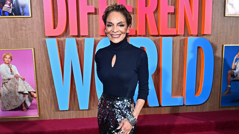 Jasmine Guy på bilden bär en svart polokragad topp och paljettkjol