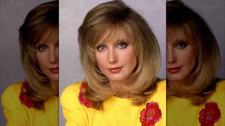 Morgan Fairchild i ett porträtt från 1990 klädd i en gul tröja med röda blomdetaljer.
