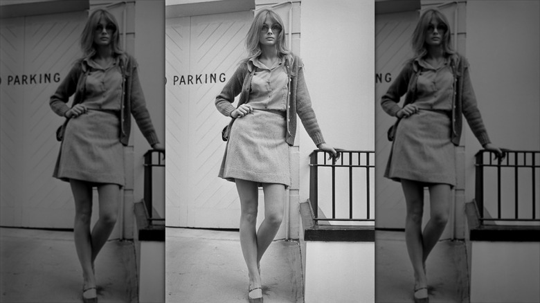 Jean Shrimpton poserar med handen på höften iförd en kort kjol och stora solglasögon