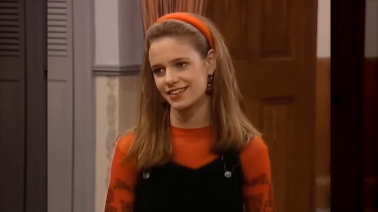 Andrea Barber bär ett orange pannband, en orange topp och svarta byxbyxor