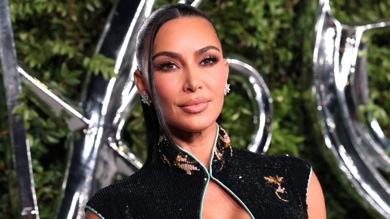 Kim Kardashian i en klänning med en asiatisk halsringning som lyser för fotot