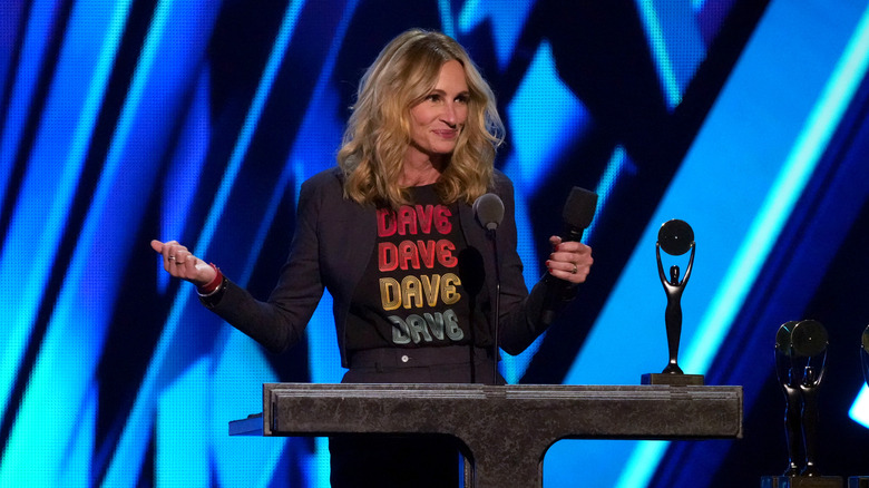 Julia Roberts lyfter sina armar medan hon talar på scenen vid ett evenemang