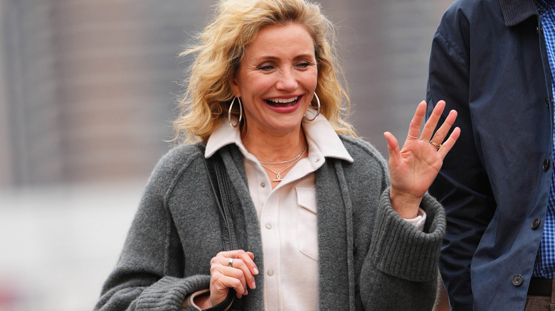 Cameron Diaz vinkar och skrattar när hon går nerför gatan