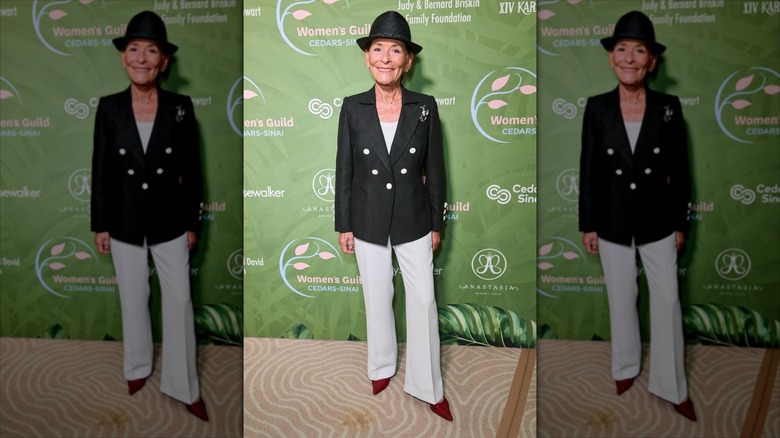 Judy Sheindlin bär en svart fedorahatt med en svart-och-gräddfärgad byxdress.