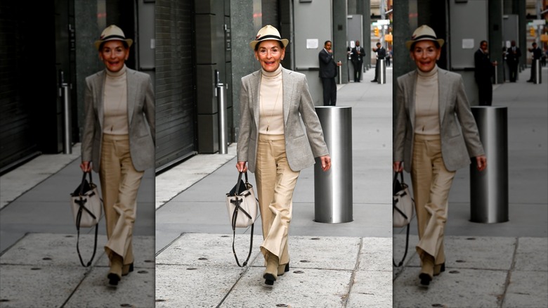 Judy Sheindlin klädd i en beige och svart fedora med en krämfärgad turtleneck med en grå kavaj.